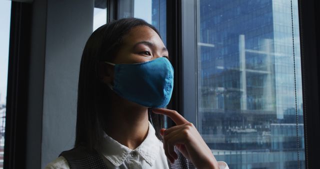 Businesswoman Wearing Mask Looking Out Window in Office Building - Download Free Stock Images Pikwizard.com