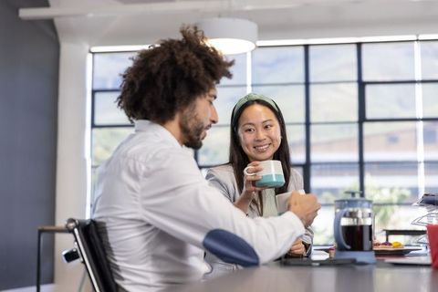 Diverse coworkers enjoying coffee and conversation in office break area