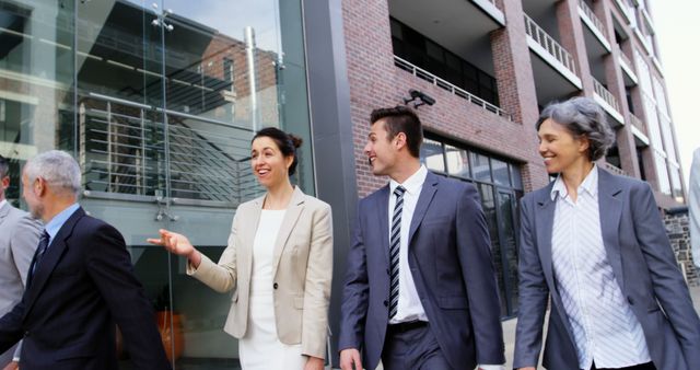 Group of business professionals walking in an urban area, casually talking. Perfect for depicting teamwork, office life, corporate culture and professional collaboration in marketing materials, company websites or business-related articles.