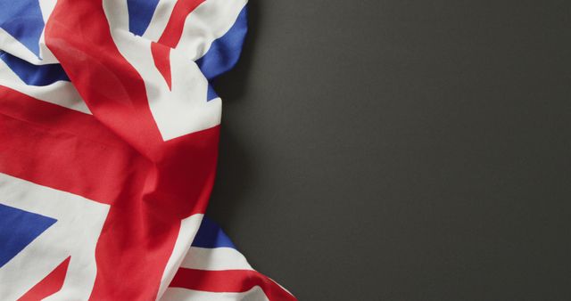 Image of creased great britain flag lying on black background. nationality, state symbols, patriotism and independence concept.