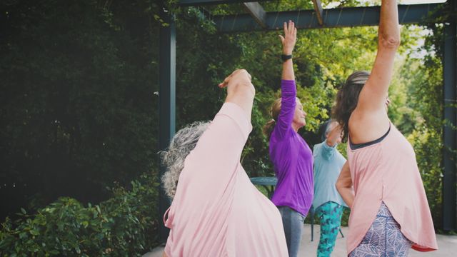 Elderly individuals practicing yoga in a natural setting promote mindfulness, health, and flexibility. Ideal for use in health and wellness blogs, senior fitness promotions, and lifestyle articles focusing on active aging.