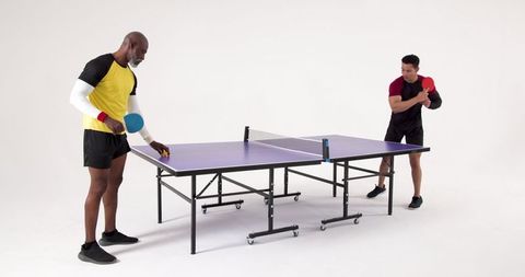 Diverse men preparing for table tennis match in modern studio