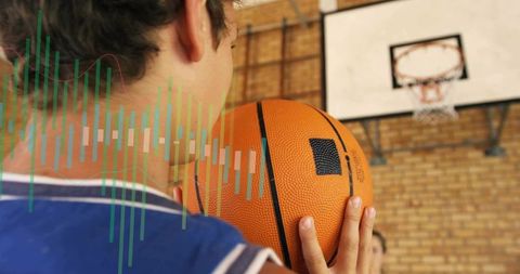 Teen basketball player preparing shot in school gym holding ball to cheek