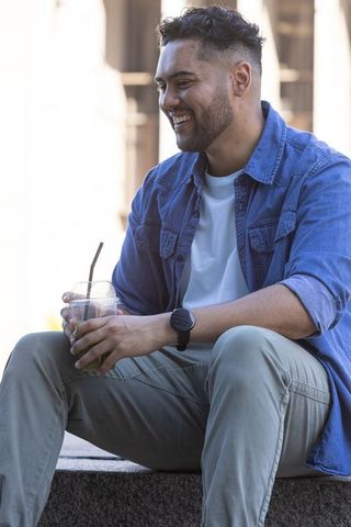 Smiling african american man relaxing with cold drink in urban casual denim outfit