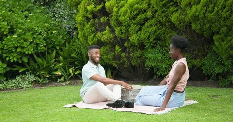 Happy Couple Having Picnic on Lawn in Sunny Park