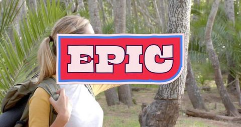 Hiker holding epic sign carrying backpack through sunlit pine and palmetto woods