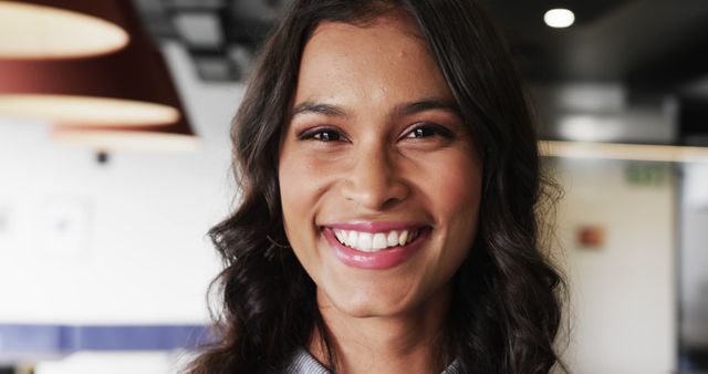 Smiling Woman with Wavy Hair in Modern Office Environment - Download Free Stock Images Pikwizard.com