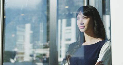 Thoughtful Businesswoman Gazing Through Window in Urban Office