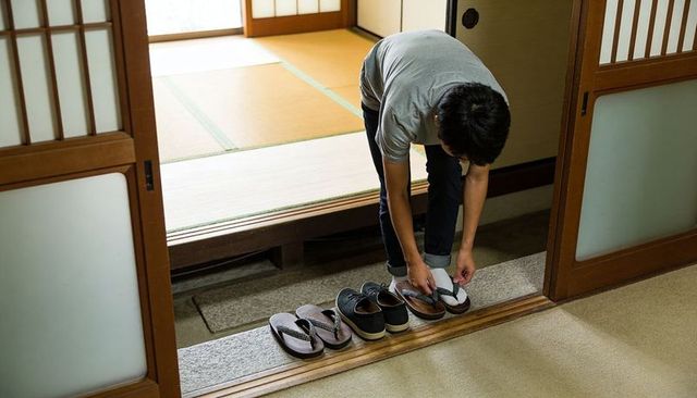 Putting on slippers at genkan in traditional japanese home with tatami and shoji doors