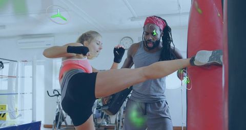 Focused Female Athlete Practicing Kicking with Motivational Trainer