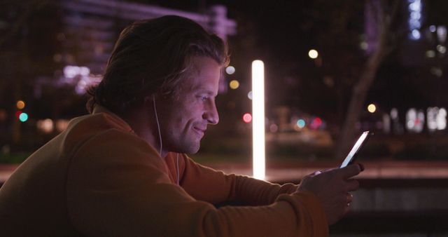 Man Smiling While Using Smartphone Outdoors at Night - Download Free Stock Images Pikwizard.com