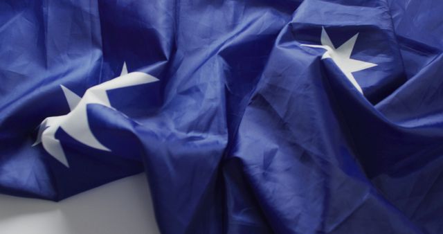This image captures a close-up view of a blue flag adorned with a star pattern commonly associated with a U.S. island territory. The fabric is crumpled and textured, adding an element of realism. Ideal for use in articles or projects related to national pride, patriotism, geography, or in any context that requires an authentic illustration of a U.S. territory flag.