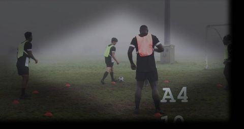 Foggy soccer practice drill with player in orange bib, cones and goal in mist