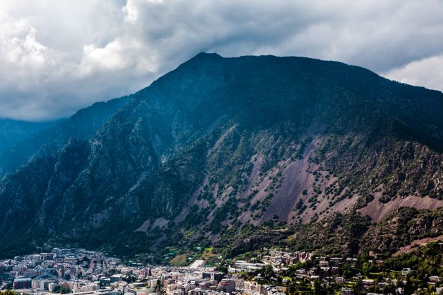 Panoramic view showcasing Andorra's magnificent mountain range with an urban landscape nestled below. Ideal for articles or content involving travel, nature, city tourism, and adventure. Can also be used in brochures or posters promoting Andorra as a travel destination.