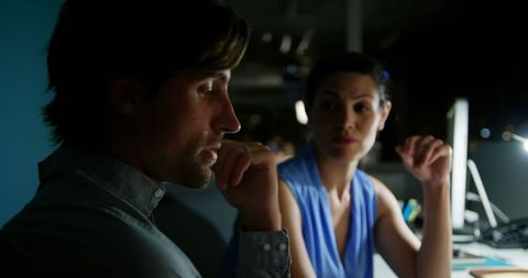 Office colleagues discussing over computer late evening