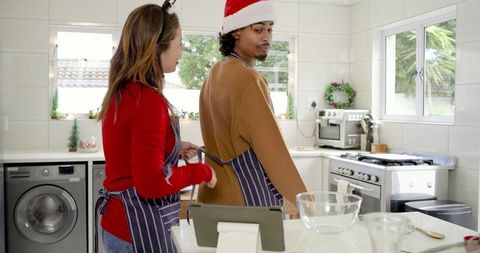 Couple tying aprons in festive kitchen preparing holiday baking and christmas traditions
