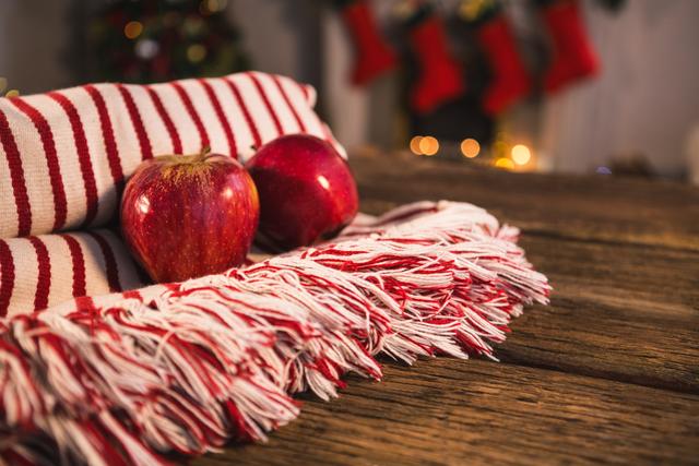 Rolled blanket with two apples on wooden table against christmas decor