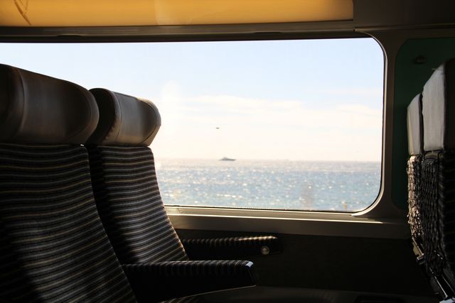 Vacant seats on a train with a stunning ocean view outside the window. This can be used for travel-related content, emphasizing peaceful journeys, scenic rides, or transportation themes. Ideal for illustrating articles or advertisements related to train travel or serene experiences.