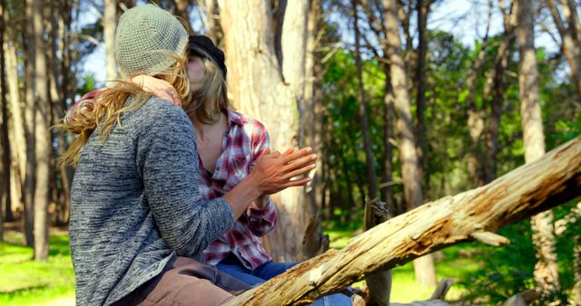Romantic young couple kissing each other in the forest. Couple sitting on tree trunk 4k