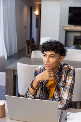 Young man in thoughtful pose at cozy home workspace