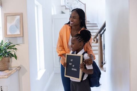 African american mother and daughter celebrating first day of school in bright entryway