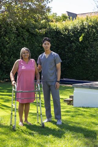 Senior woman with walker and caregiver in tranquil garden setting