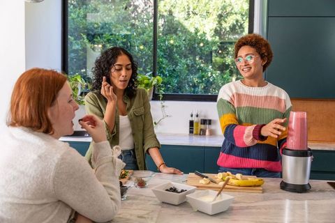 Friends enjoying smoothie preparation in modern kitchen