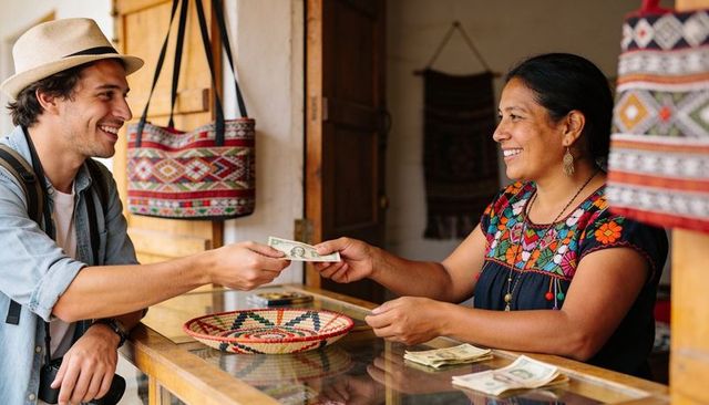 Traveler paying artisan at colorful textile stall, exchanging cash for handmade goods
