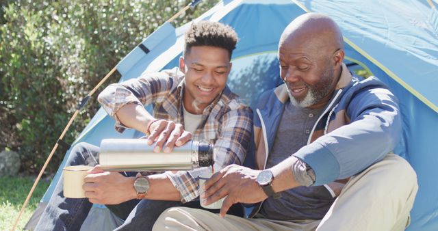 Happy african american father and adult son sitting outside tent drinking coffee in sun - Download Free Stock Photos Pikwizard.com