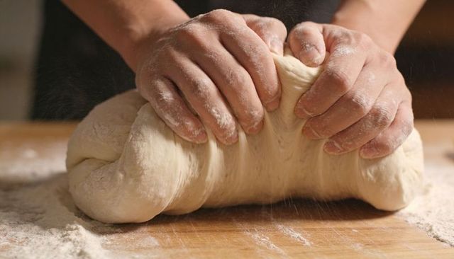 Hands Kneading Soft Bread Dough on Floured Wooden Board Closeup for Baking Content