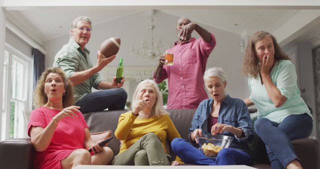 Image of happy diverse senior friends cheering while watching american football match in tv. retirement lifestyle, spending quality time with friends.