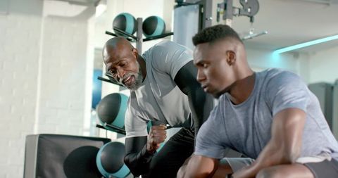 African american trainer coaching young man during strength training session in gym