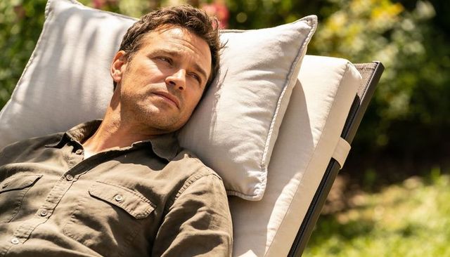Sunlit contemplative man relaxing on backyard lounge chair with cushion and khaki shirt