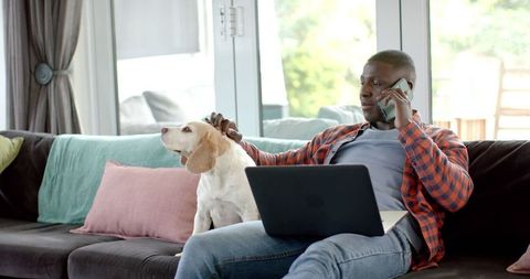 Man engaging in remote work with laptop and dog by side