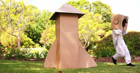 Child playing in homemade cardboard rocket costume in garden