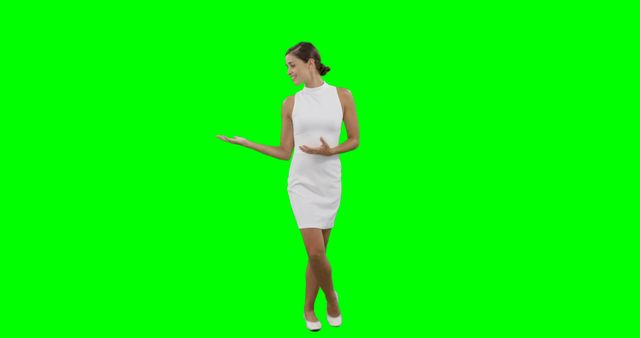 A young Caucasian woman in a white dress is presenting something with her hand, with copy space on a green screen background. Her gesture suggests she might be showcasing a product or feature in a commercial or presentation.