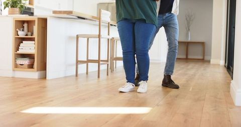Mature couple standing on hardwood kitchen floor showcasing sneakers and boots