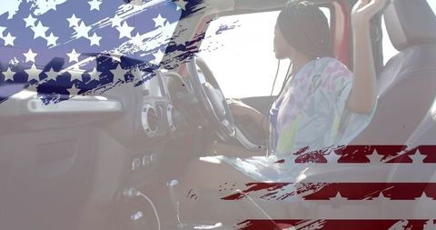 Contemplative woman with braids holding steering wheel in sunlit car, flag overlay