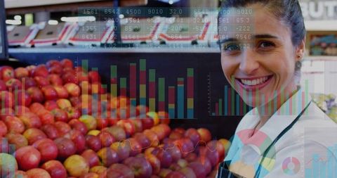 Clerk with financial charts overlaying apples in grocery store