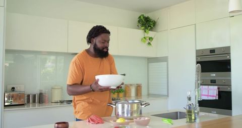 African american man preparing meal in modern minimalist kitchen stirring mixing bowl