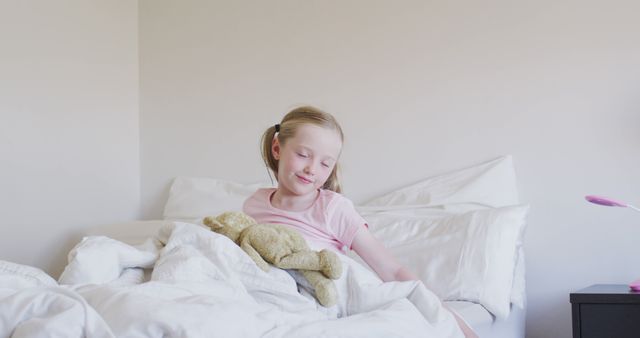 Happy caucasian girl sitting up in bed with teddy bear in the morning - Download Free Stock Photos Pikwizard.com