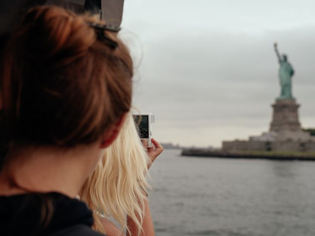 Tourists on a ferry capturing a photo of the Statue of Liberty in New York City. Perfect for use in travel blogs, tourism advertisements, and promotional materials highlighting iconic landmarks and tourist activities.