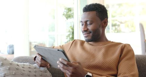 Relaxing at Home Man Using Tablet on Sofa Wearing Smartwatch Casual Modern Lifestyle