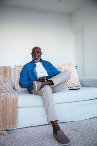 Senior man relaxing on sofa with mug in modern living room