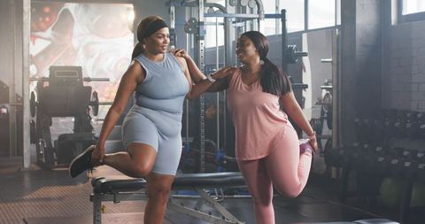 Plus-size black friends stretching together at gym promoting confidence and wellness daily
