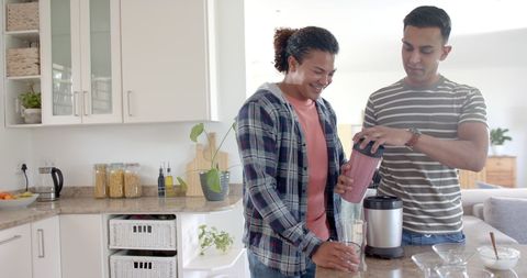 Happy Beard and Flannel Couple Blending Smoothie in Bright Kitchen