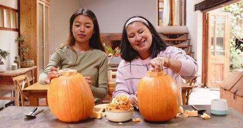 Grandmother and Granddaughter Carving Pumpkins at Home for Halloween