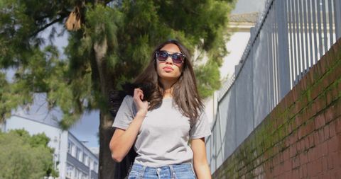Fashionable Young Woman Walking Among City Trees