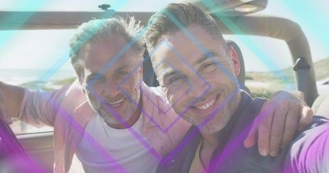 Smiling mature men taking selfie in convertible on coastal road during sunny drive