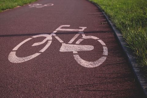 Red asphalt bicycle path with painted signage in park